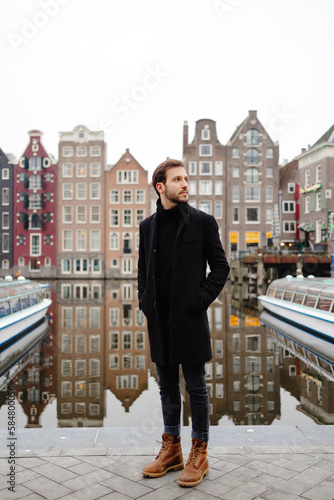 Gentleman posing on quay near river in old city photo