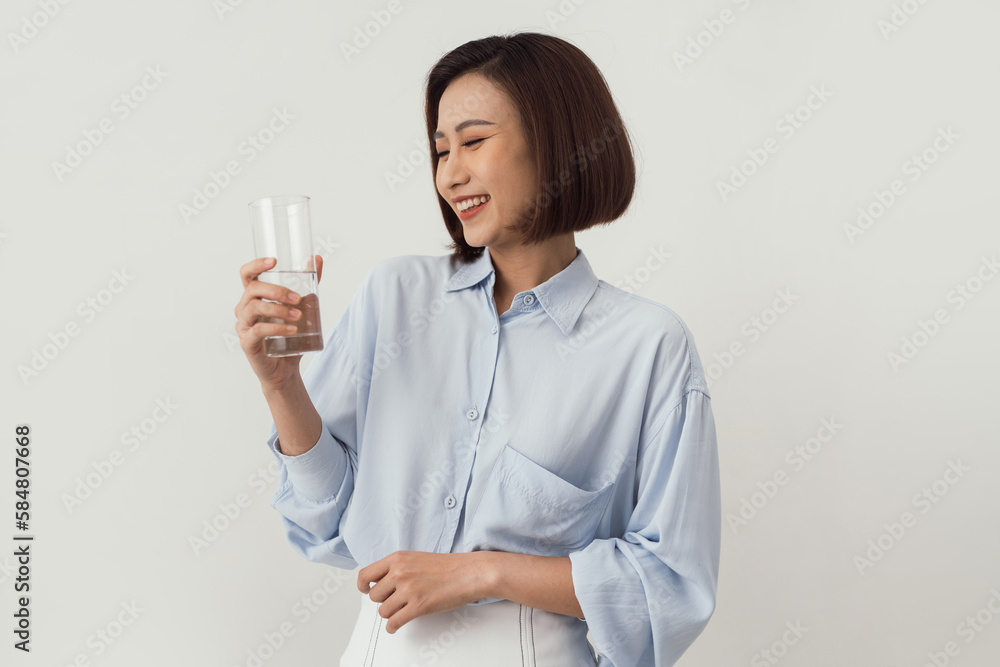 Gorgeous woman holding a glass of water while standing against a Gorgeous woman holding a glass of water while standing against a