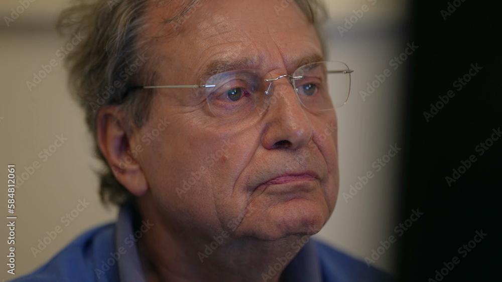Senior man reading content online in front of computer screen. One mature older male 70s person browsing internet closeup face Senior man reading content online in front of computer screen. One mature older male 70s person browsing internet closeup face