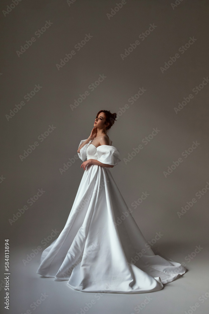 Full length fashionable german bride lady in white wedding dress, looking away. Stylish cute cover brunette woman posing at grey background. Fashion trendy style beauty concept. Copy ad text space