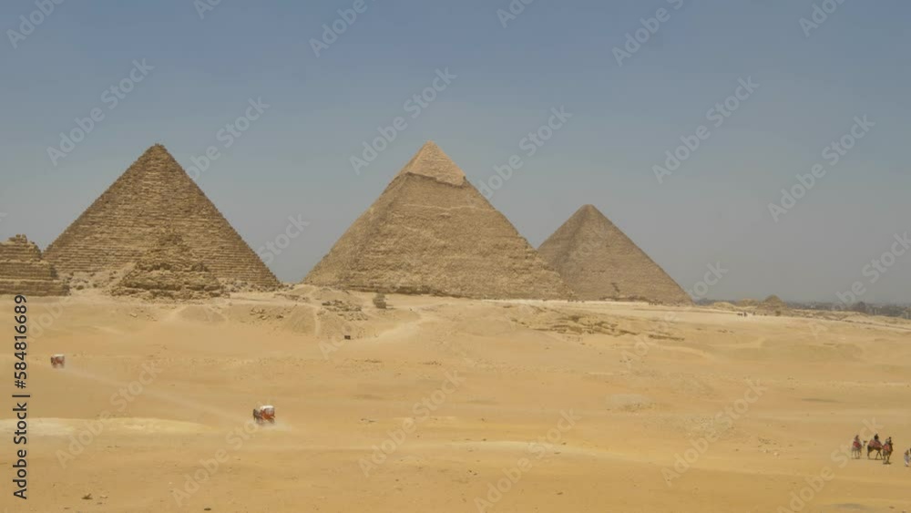 2022 - Tourists ride camels or in horse-drawn wagons past the pyramids of Giza. 2022 - Tourists ride camels or in horse-drawn wagons past the pyramids of Giza.