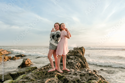 Fun portrait of teen sisters posing with handguns on beach photo