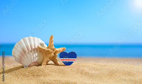 Beautiful beach in the Cape Verde. Flag of Cape Verde in the shape of a heart and shells on a sandy beach.