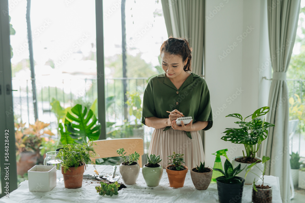 happy smiling woman with notebook and pencil planting pot flowers happy smiling woman with notebook and pencil planting pot flowers