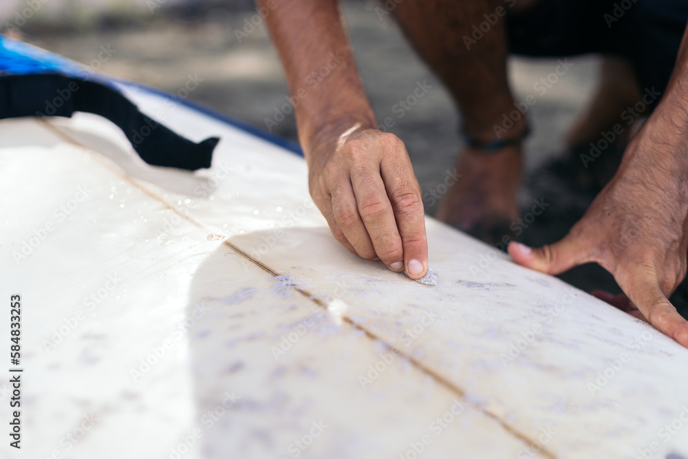 Unrecognizable surfer putting surf wax on the board Unrecognizable surfer putting surf wax on the board
