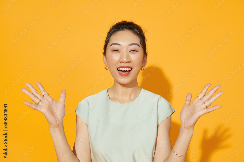 Surprised happy asian woman looking at the camera over yellow Surprised happy asian woman looking at the camera over yellow