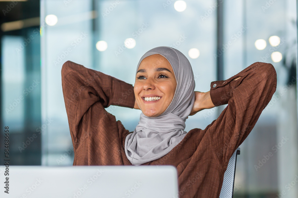 A dreamy and smiling young Arab woman in a hijab is sitting in the ...