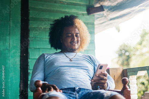 Man using smartphone on the porch of a wooden house photo