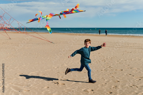 Boy running on a beach with a kite photo