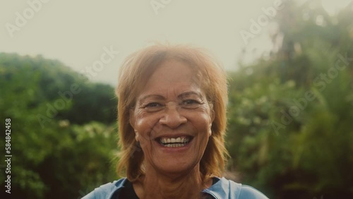 Happy senior Latin woman having fun smiling in the camera after training activity in a public park