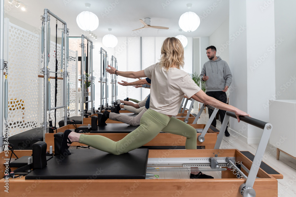 Group of people exercising on Pilates reformers Group of people exercising on Pilates reformers