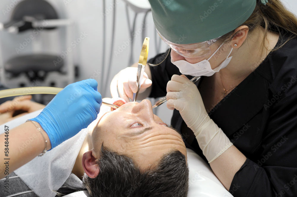 adult man praying with his eyes looks at the doctor who tears his tooth dentistry hurts the request of man woman pull a tooth out adult man praying with his eyes looks at the doctor who tears his tooth dentistry hurts the request of man woman pull a tooth out