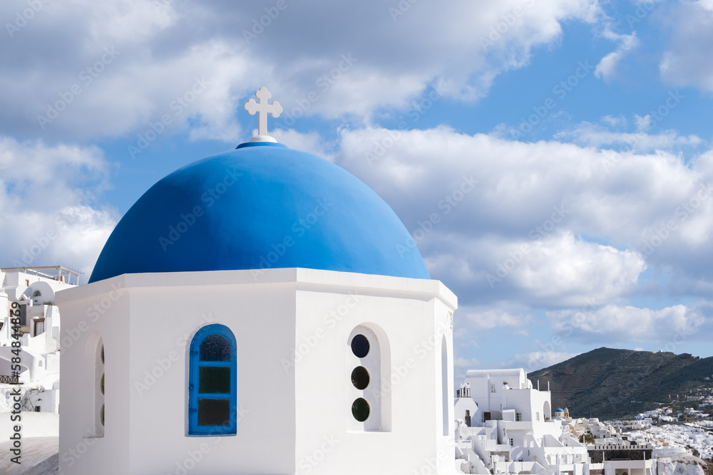 View of white houses and greek church with blue dome in Oia, Santorini