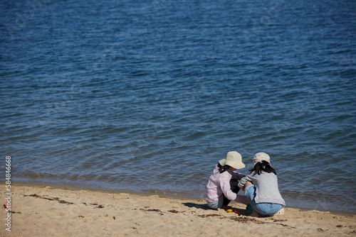 海水浴場の砂浜で遊んでいる二人の小学生の女の子の姿