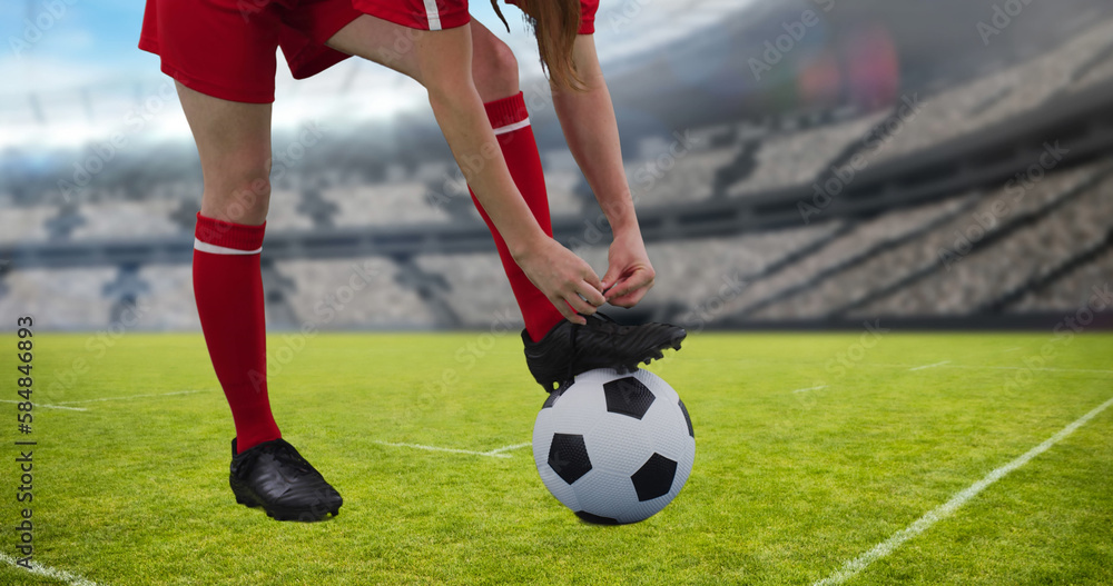 Composition of caucasian female football player tying shoelaces over stadium