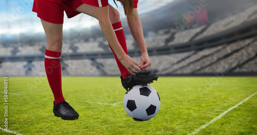 Composition of caucasian female football player tying shoelaces over stadium © vectorfusionart