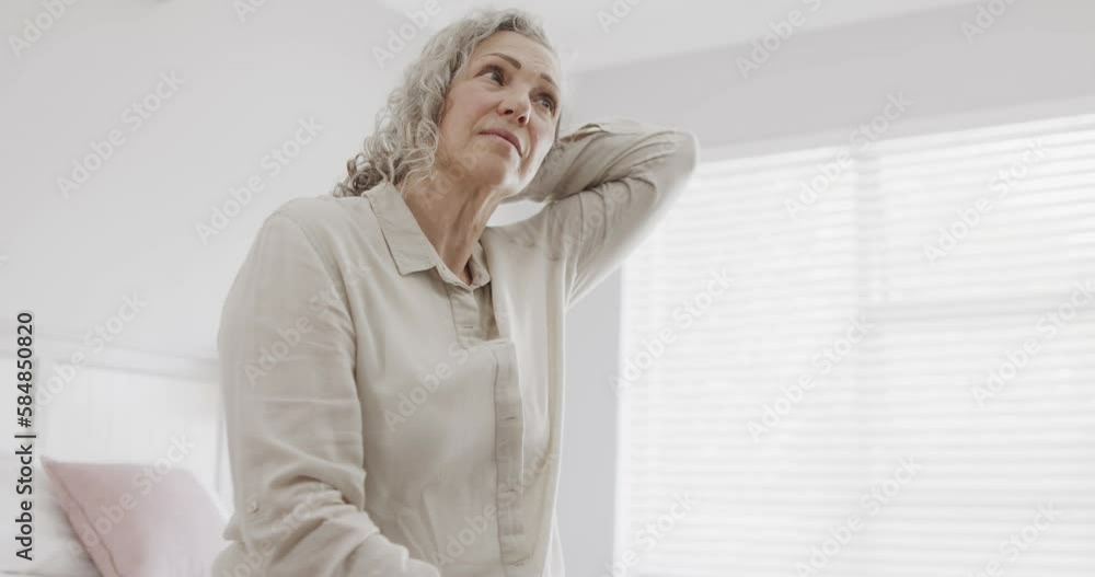 Senior caucasian woman sitting on bed and massaging neck, slow motion Senior caucasian woman sitting on bed and massaging neck, slow motion