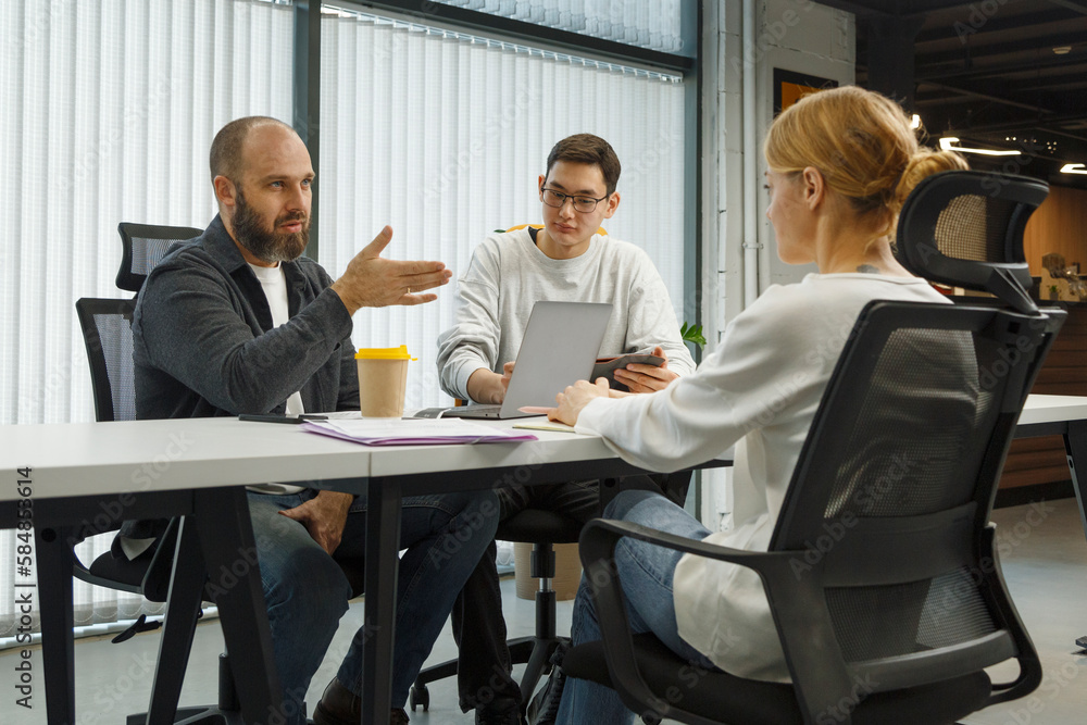 Serious diverse coworkers talking at table in office
Serious diverse coworkers talking at table in office