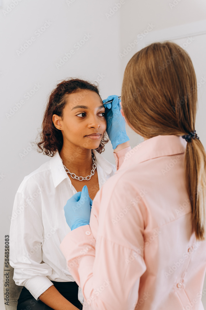 Beautician plucking eyebrows with tweezers Beautician plucking eyebrows with tweezers