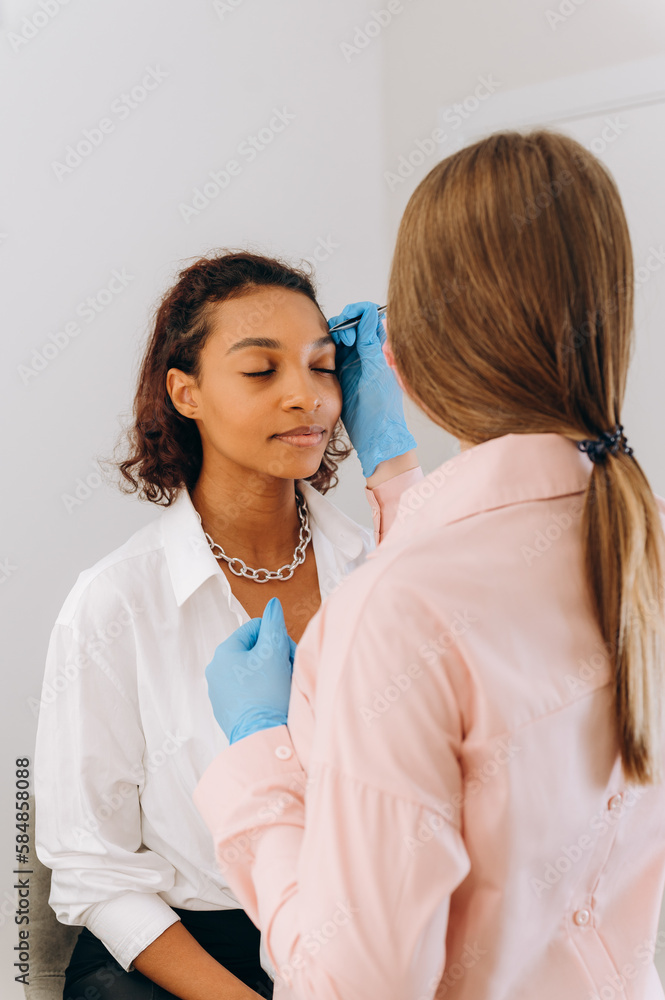 Beautician plucking eyebrows with tweezers Beautician plucking eyebrows with tweezers