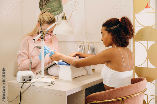 Black lady getting manicure in beauty studio