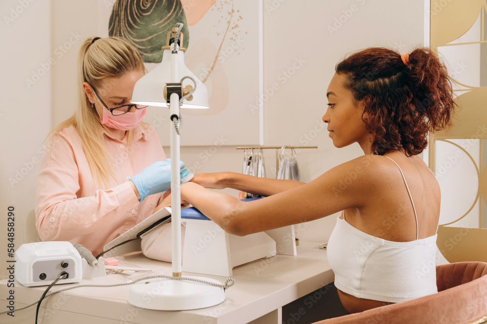 © Alina Hvostikova/Stocksy - Smiling black woman getting manicure © Alina Hvostikova/Stocksy - Smiling black woman getting manicure