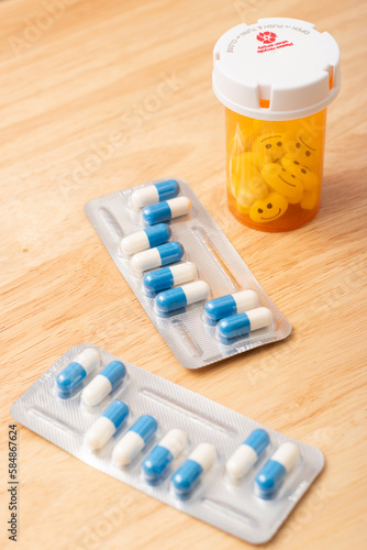 Vertical view of tablets of pills and capsule of pill with happy and sad faces
