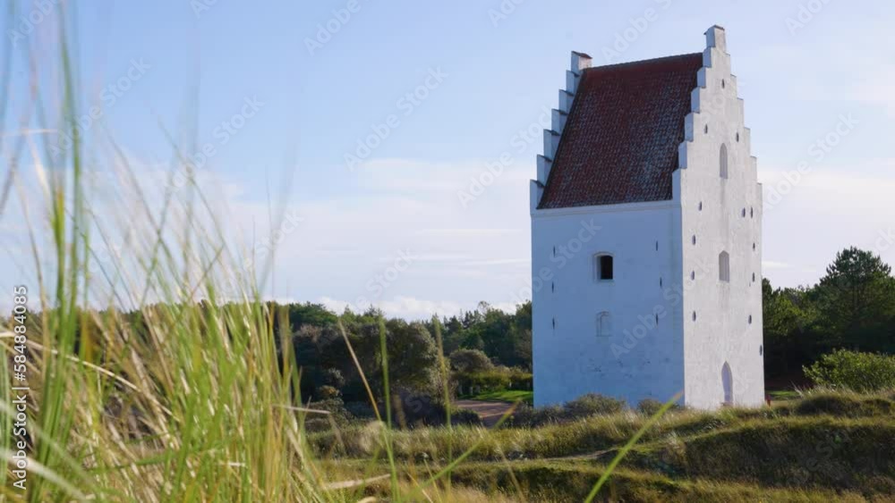 2022 - Tall grass rustles in the wind outside the Den Tilsandede Kirke (the sand-covered church) in Skagen, Denmark on a sunny day. 2022 - Tall grass rustles in the wind outside the Den Tilsandede Kirke (the sand-covered church) in Skagen, Denmark on a sunny day.