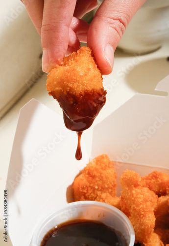 hand dipping nugget in sauce