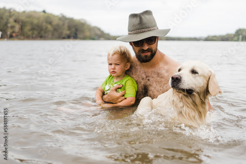 man supports his son and dog in water
