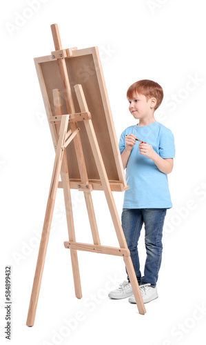 Little boy painting against white background. Using easel to hold canvas