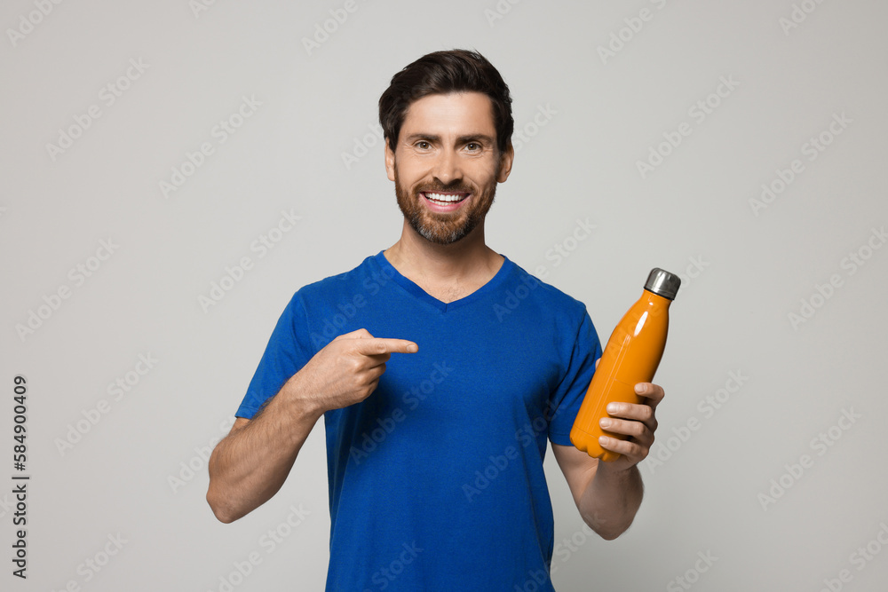Man pointing at orange thermo bottle on light grey background Man pointing at orange thermo bottle on light grey background