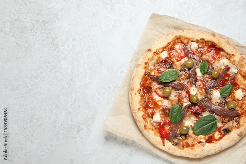Tasty pizza with anchovies, basil and olives on white table, top view. Space for text