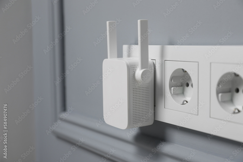 Wireless Wi-Fi repeater on light grey wall, space for text
