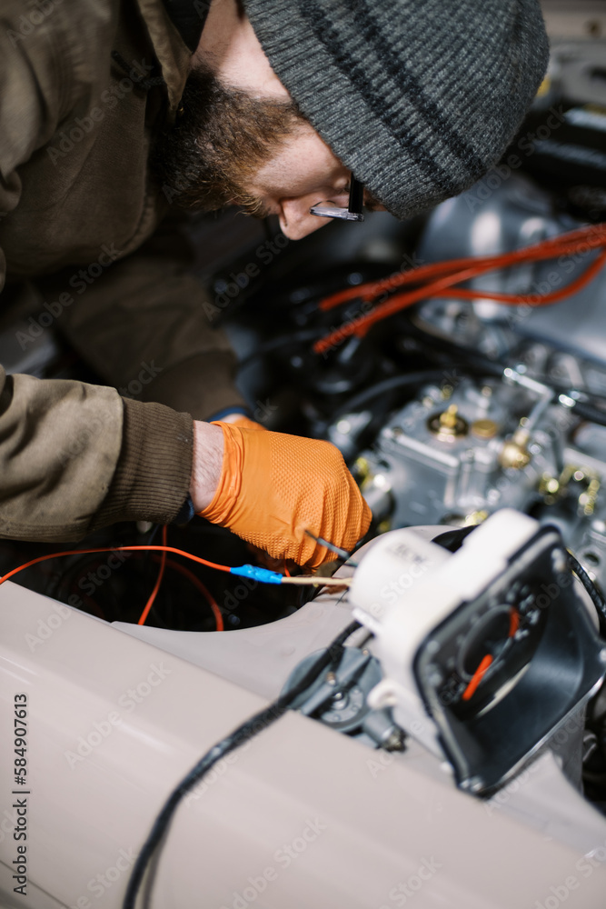 millennial man in winter clothing working on old car millennial man in winter clothing working on old car