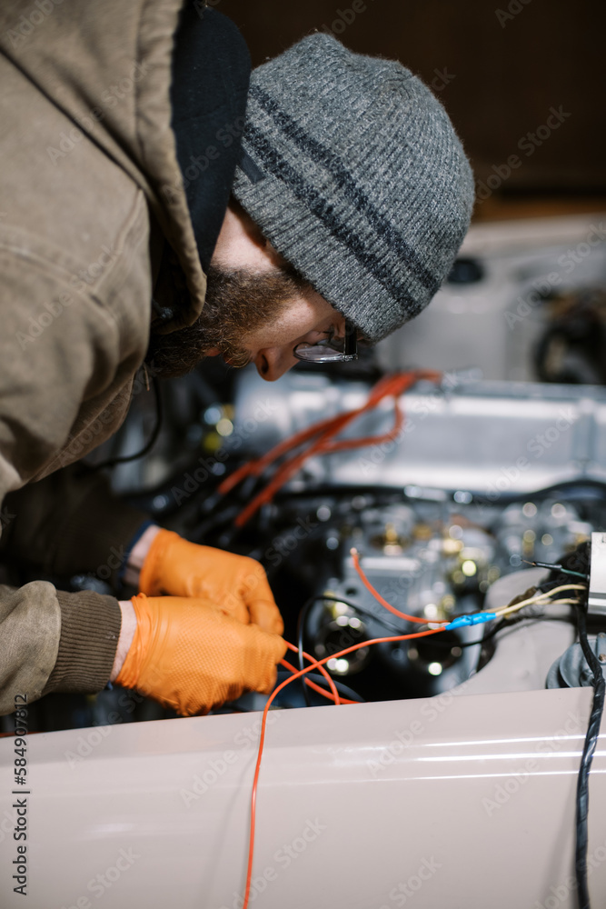 millennial man in winter clothing working on old car millennial man in winter clothing working on old car