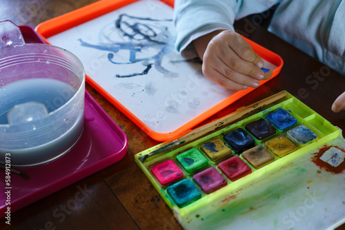 Close up on child hand painting with watercolor.  photo