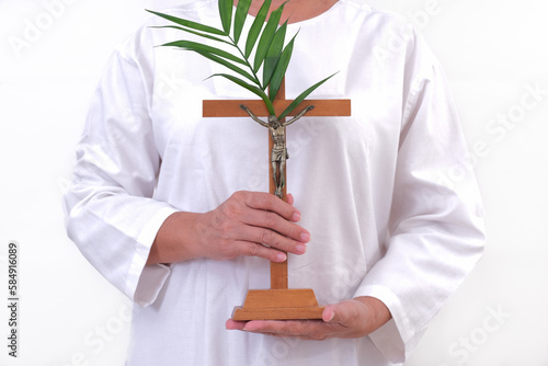 Close-up: A woman's hand holds a wooden cross decorated with palm leaves. photo