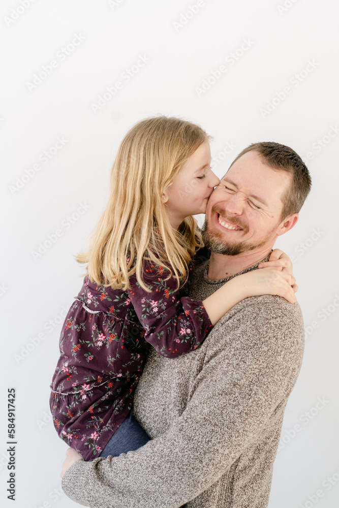 Happy & smiling father, daughter kiss dad on cheek Happy & smiling father, daughter kiss dad on cheek