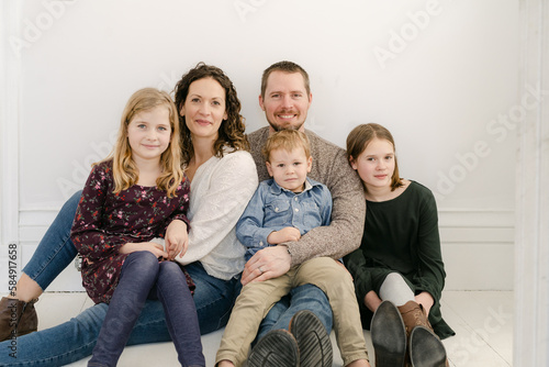 Happy & loving family of five sitting onwhite floor  photo