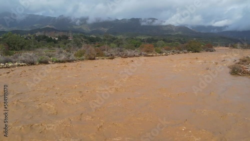 2023 - Excellent aerial footage wending up the flooded Ventura River in Ojai, California towards misty mountains. photo