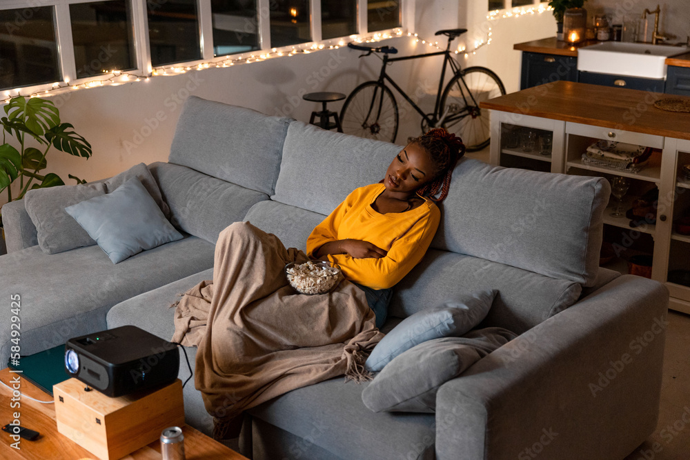 black woman watching a movie with a projector in her apartment
black woman watching a movie with a projector in her apartment