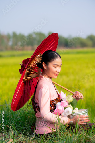 Pretty Asian women in traditional Thai dress. Beautiful traditional Thai dresses by Asian Buddhists make merit at the Temple a tourist attraction, a