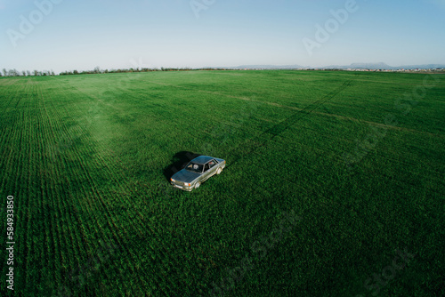Car in middle of green wheat field
