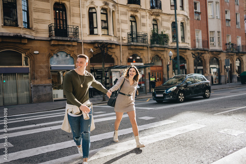 Joyful couple holding hands on pedestrian crossing photo