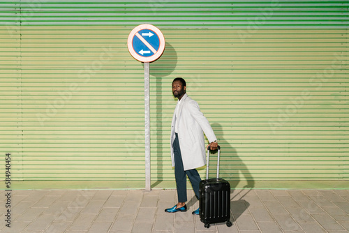 Black man with baggage near traffic sign photo