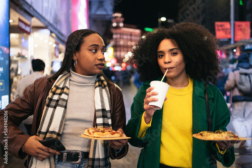 Young black women eating fast food on the street at night