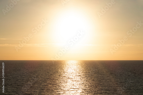brown sea water surface and big bright sun in the yellow sky