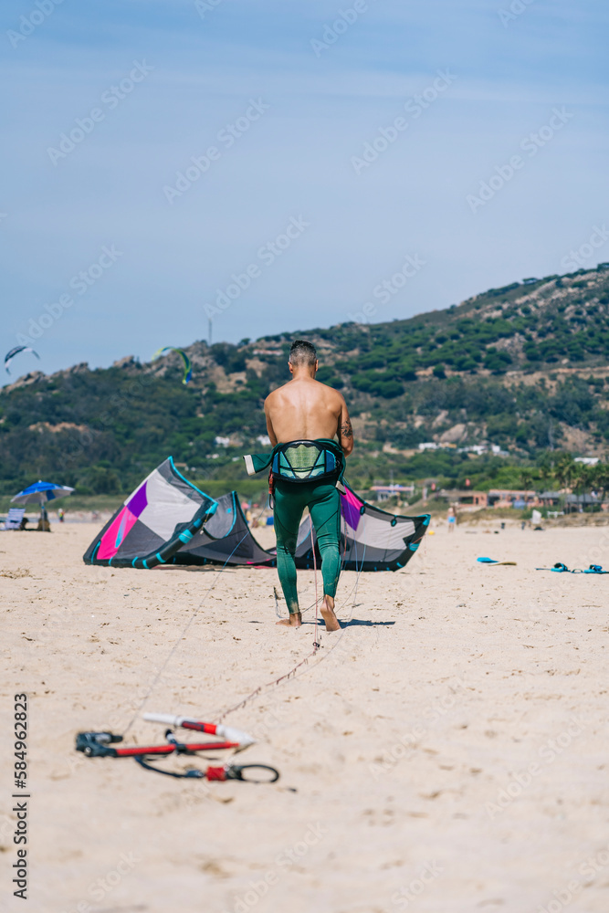 Male kitesurfer putting on wetsuit on beach Male kitesurfer putting on wetsuit on beach