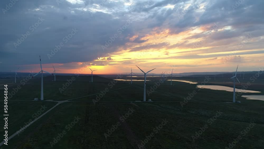 Aerial view of windmills farm in the fields. World energy power crisis. Green energy production concept. Wind power turbines generating clean renewable energy.